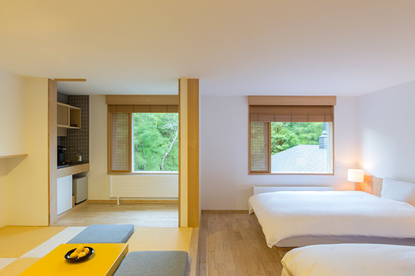 デラックスルームRoom205　桐の無垢材を用いた床に、ナチュラルな北欧家具。和室には、居心地の良い座椅子とローテーブルをご用意。中庭に面した人気のお部屋です。